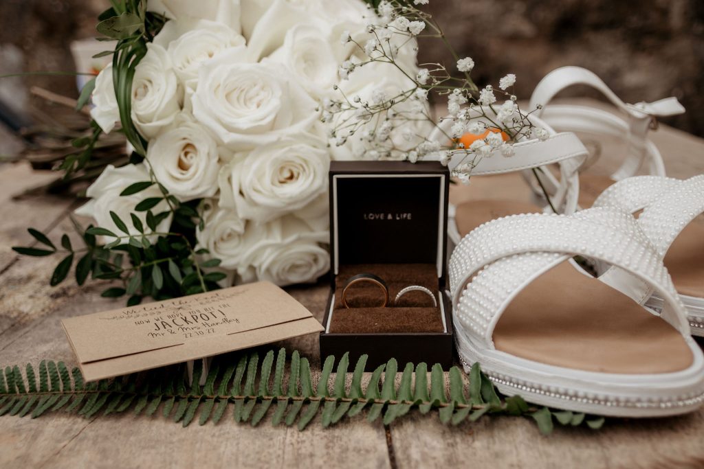 Wedding details such as shoes, rings, flowers and invite.